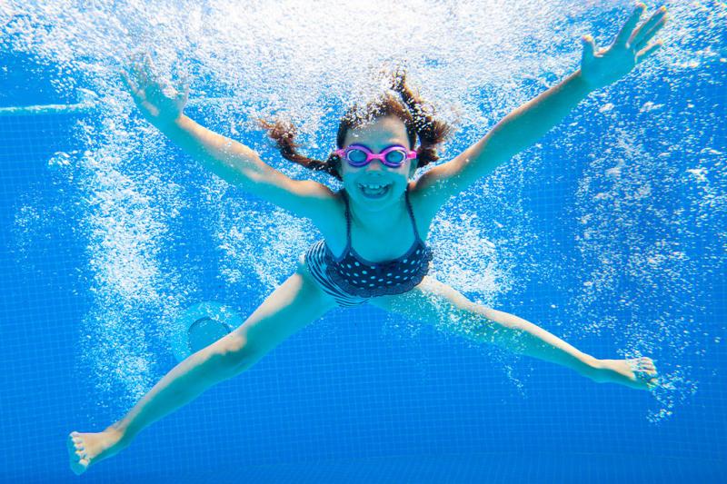 Girl making a splash underwater at a swimming pool